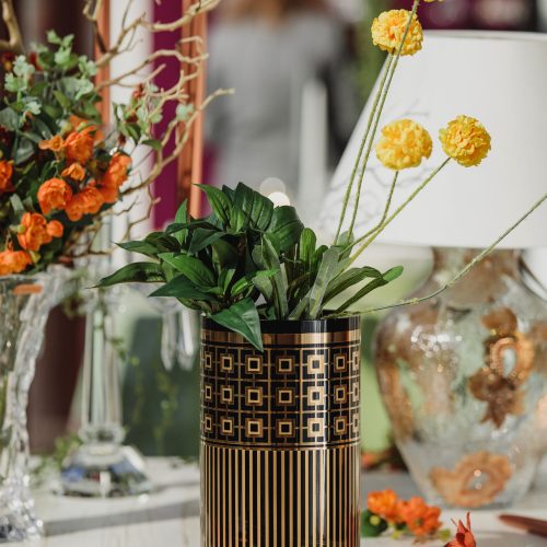 side view of modern glas vase with geometric pattenr with yellow flowers on a wooden table
